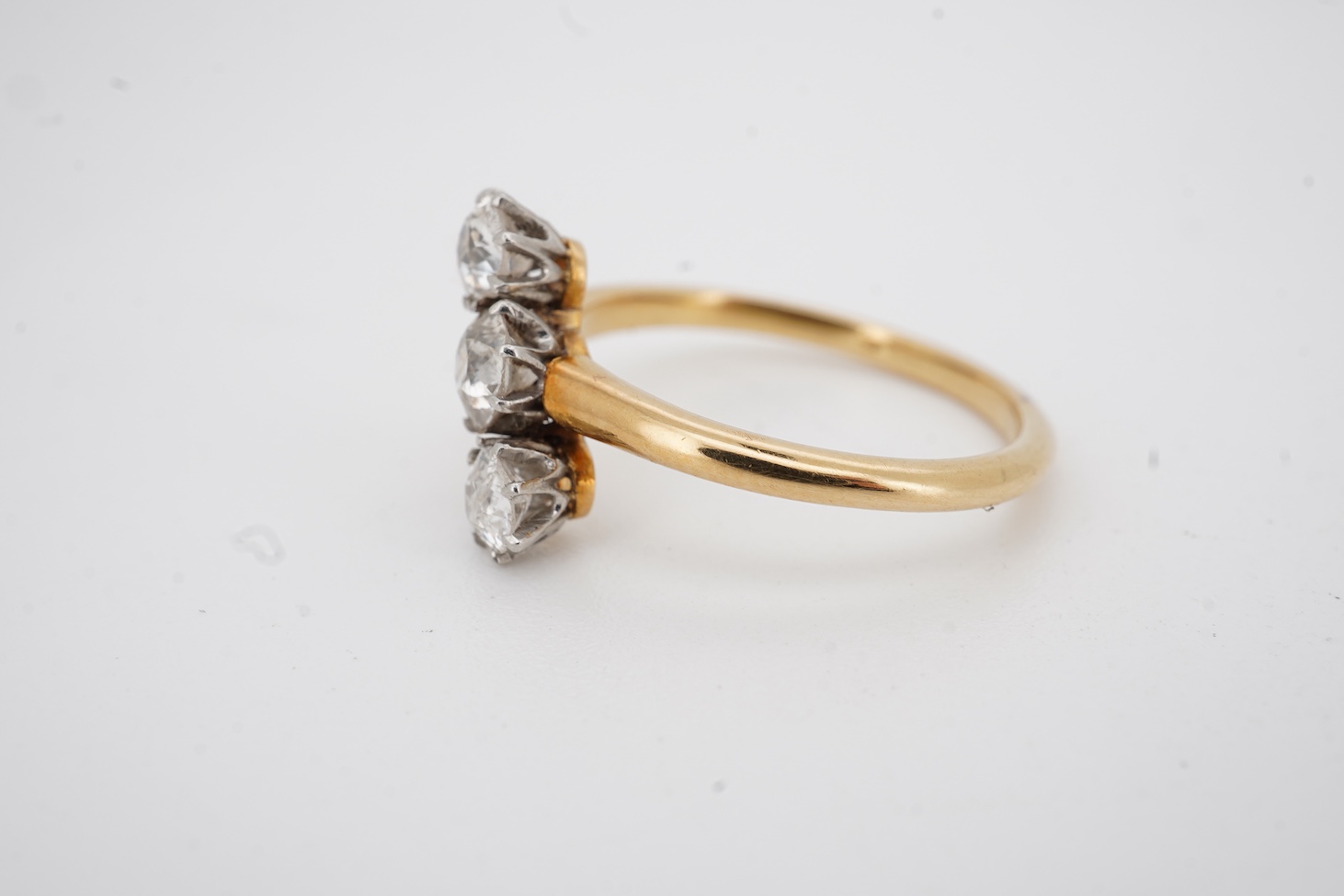 A mid to late 20th century yellow metal and three stone diamond set crossover ring, total diamond weight approx. 0.45-0.50ct, size K, gross weight 2.5 grams.